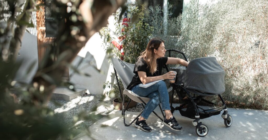 A mother sitting outdoors enjoying a sunny day with her baby in a stroller.